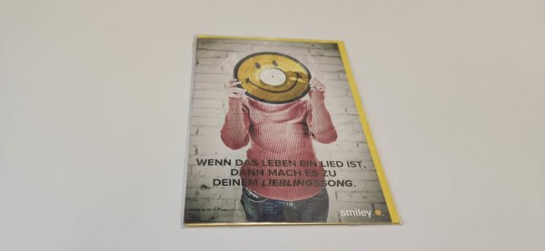 Allgemeine Wünsche – Glückwunschkarte im Format 11,5 cm x 17,5 cm mit Umschlag – Serie: Smiley – Frau mit Smileyplatte vor dem Gesicht